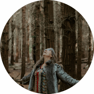 Naturterapeut, naturarbejder, shaman og healer Jeanne Jensen fra Naturlig Viis danser iført en kjole og pels i skoven til en årstidsfejring eller et møde i forbindelse med årstidshjul