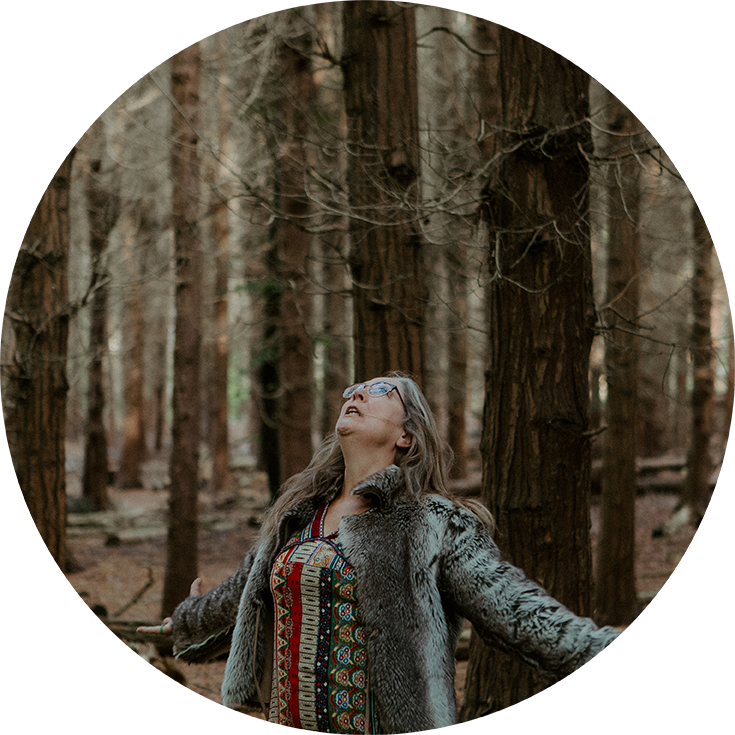 Naturterapeut, naturarbejder, shaman og healer Jeanne Jensen fra Naturlig Viis danser iført en kjole og pels i skoven til en årstidsfejring eller et møde i forbindelse med årstidshjul